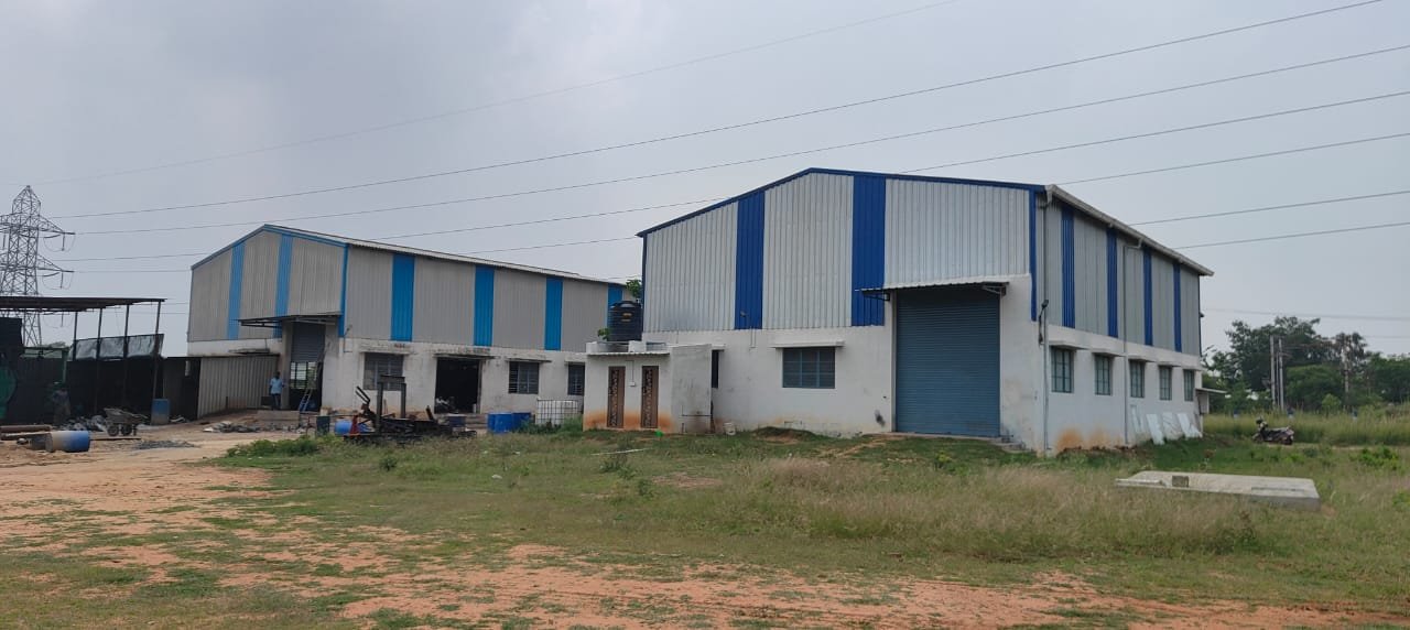 Two industrial factory buildings side by side with blue stripe cladding at Vedanth Industrial Zone