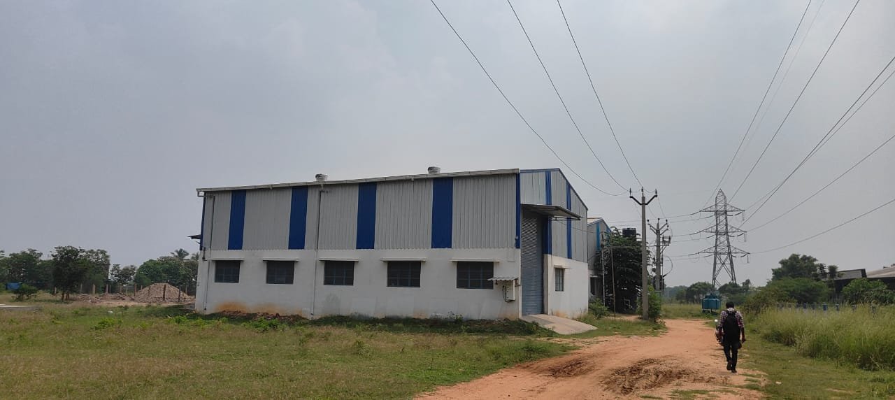 Long side elevation of industrial factory building showing multiple windows and blue cladding